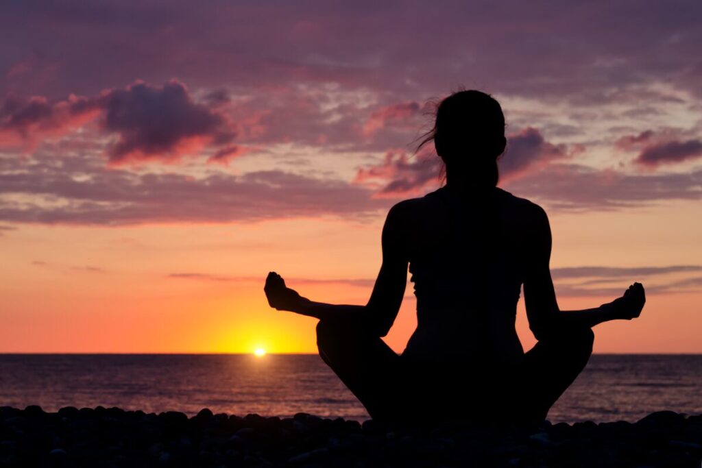 A woman in a seaside doing mindfulness. How to cultivate an unbreakable mindset.
