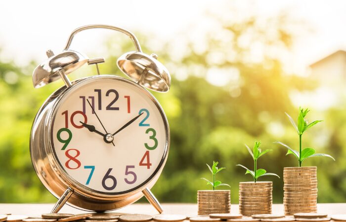 How to do mindfulness for beginners 3 A golden alarm clock and three files of coins with few pieces of small plants. How to do mindfulness for beginners