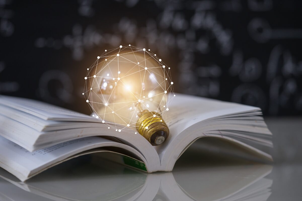 An open white book with bulb in a desk. How a simple shift in mindset can change your life forever.