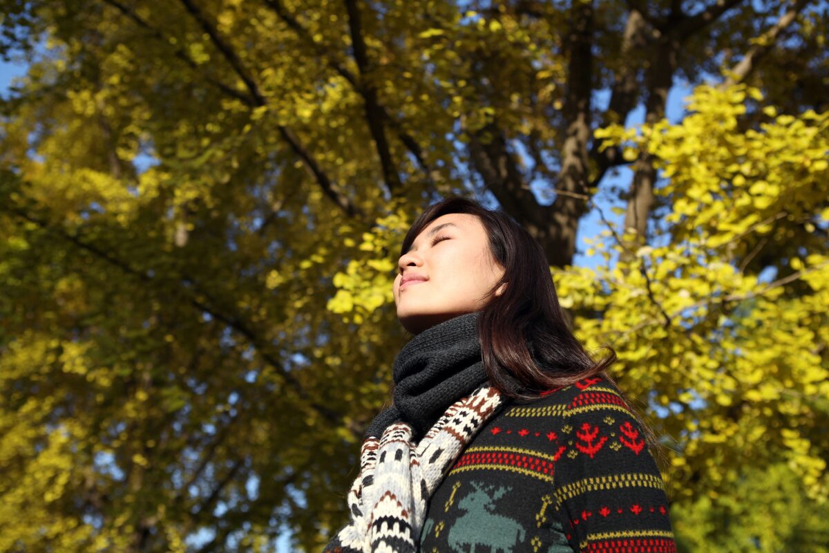An asian woman doing deep breathing exercise at the park. How to manage anger: Strategies to regulate your anger.
