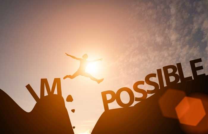 A mid air jumping through a mountains demonstrating the word possible. 10 powerful motivational strategies to achieve your dreams.