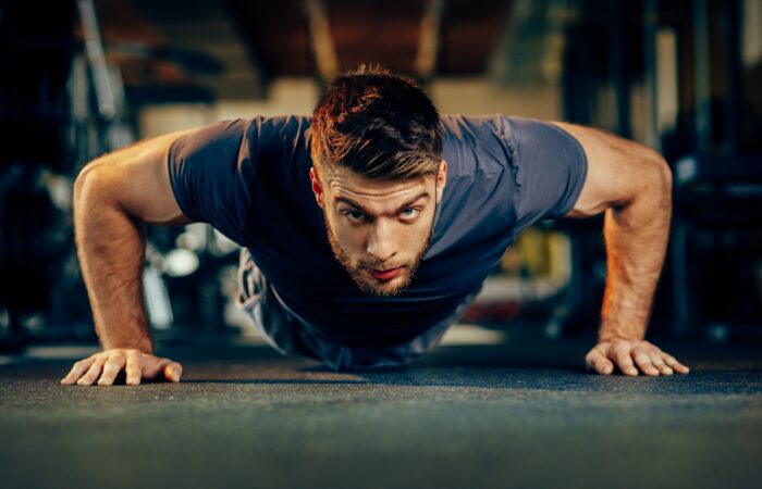 A young man in a push up position in a gym. How to cultivate an unbreakable mindset through positive thinking